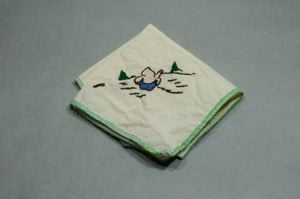 Image: Figure sitting with back turned, one of a set of 4 embroidered napkins, each with figure at play